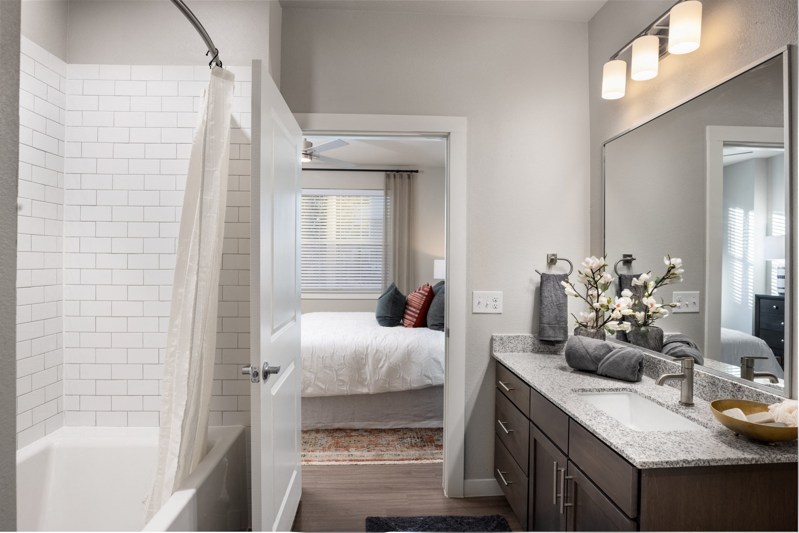 bathroom with shower and sink and bedroom with bed in the background